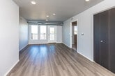 This single-floor unit offers a thoughtfully designed layout with a clean, contemporary aesthetic throughout. The open living area features light-toned hardwood-style flooring, recessed lighting, and large glass doors that invite natural light while providing access to a private balcony with outdoor views. A built-in closet with dark-finished doors adds functional storage to the living space.

The kitchen is outfitted with dark gray cabinetry, light granite-style countertops, and black appliances including a range, microwave, dishwasher, and refrigerator. The layout maximizes counter and cabinet space, making it both practical and visually cohesive.

The bedrooms are carpeted for comfort, each featuring neutral tones and dark-accented doors. One bedroom includes a walk-in closet with built-in shelving, while additional rooms offer generous wall space and ventilation. Two full bathrooms serve the unit; one includes a vanity with dark cabinetry and granite-style countertops paired with a walk-in shower, while the second features a full tub-shower combination and tile flooring.

A dedicated laundry area houses a full-size washer and dryer with overhead shelving, completing this well-organized and modern living space.