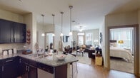 Located at 1345 Tenth Ave E in Tuscaloosa, Alabama, this single-story residence offers a well-designed, open-concept layout that seamlessly connects the kitchen and living areas. The kitchen is a functional centerpiece, featuring dark cabinetry, granite countertops, a breakfast bar with seating, and stylish pendant lighting that draws the eye upward to the soaring ceilings. Wood-look flooring extends throughout the main living areas, adding warmth and continuity to the space.

The living room is bright and inviting, benefiting from large windows that allow generous natural light to fill the room. A ceiling fan adds comfort, while the open flow from the kitchen creates an ideal setting for both everyday living and entertaining.

The bedrooms are carpeted for comfort and offer ample space, with each room featuring neutral tones and easy access to the hallways. The primary bathroom includes a granite-topped vanity with dark cabinetry, a combined tub and shower, and wood-look tile flooring. A second full bathroom mirrors this design, providing consistent finishes throughout. The overall ambiance of this residence is clean, modern, and functional, making it a practical and comfortable home in Tuscaloosa.