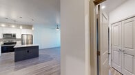 Located in Colorado Springs, CO, this well-appointed one-bedroom, one-bathroom unit offers a thoughtfully designed single-floor layout with a comfortable sense of space. The open-concept living and kitchen area is anchored by light wood-look flooring, neutral-toned walls, and a ceiling fan, creating a bright and airy atmosphere. Natural light filters in through windows, enhancing the clean, modern aesthetic throughout.

The kitchen is a standout feature, boasting white shaker-style cabinetry with sleek hardware, granite-look countertops, a tile backsplash, and a full suite of stainless steel appliances including a refrigerator, electric range, microwave, and dishwasher. A dark-finished island with pendant lighting provides additional prep space and casual seating.

The bedroom offers plush carpeting, a ceiling fan, and dual windows that allow ample natural light and views of the surrounding community. A dedicated closet provides practical storage. The bathroom includes a full tub-and-shower combination with floor-to-ceiling tile surround and wood-look flooring.

A separate laundry room houses a full-size washer and dryer, adding everyday convenience. The overall design balances modern finishes with functional living, making this a practical and attractive unit in North Colorado Springs.
