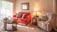 Located at 3802 Towne Point Rd in Portsmouth, Virginia, this single-floor residence offers a thoughtfully arranged layout with multiple living spaces designed for comfort and functionality. The living room serves as a welcoming centerpiece, featuring large sliding glass doors dressed with vertical blinds that flood the space with natural light and provide outdoor views. Soft carpeting and neutral walls create a warm, inviting atmosphere throughout.

The kitchen is efficiently designed with light wood cabinetry, dark countertops, and tile flooring. It includes a full suite of white appliances — a refrigerator, electric range, and dishwasher — alongside ample storage and counter space. A convenient pass-through window connects the kitchen to the dining area, where a cozy four-seat dining nook offers a casual setting for meals.

The primary bedroom is generously sized, benefiting from multiple windows that bring in abundant natural light, and includes a double closet with built-in shelving. Additional bedrooms also feature carpeted floors, closets, and windows with outdoor views, making each room comfortable and functional. The bathroom is finished with tile flooring, light wood vanity cabinetry, and a shower-tub combination. Throughout, the residence maintains a clean, neutral aesthetic with practical finishes.