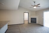This single-floor residence offers a thoughtfully designed layout that balances comfort and functionality. The open-concept living area is a standout feature, boasting vaulted ceilings, a ceiling fan, and soft carpeted flooring. A sliding glass door with vertical blinds floods the space with natural light and provides access to the outdoors, creating an airy and inviting atmosphere.

The kitchen is well-equipped and stylish, featuring rich dark-brown cabinetry, granite-style countertops, and a full suite of stainless steel appliances including a refrigerator, electric range, microwave, and dishwasher. A kitchen island provides additional prep space and storage, while light wood-tone vinyl plank flooring ties the space together seamlessly.

The bedrooms are generously sized, each featuring plush wall-to-wall carpeting, neutral-toned walls, and windows with blinds that allow for natural light and outdoor views. Several rooms include ceiling fans for added comfort. The bathroom is clean and functional, offering a full soaking tub and shower combination, a vanity with granite-style countertops, dark cabinetry, and wood-tone flooring, complemented by a window for natural ventilation.

Throughout the residence, consistent design choices — including dark baseboards, neutral wall tones, and a cohesive mix of carpet and vinyl plank flooring — create a unified and modern aesthetic.