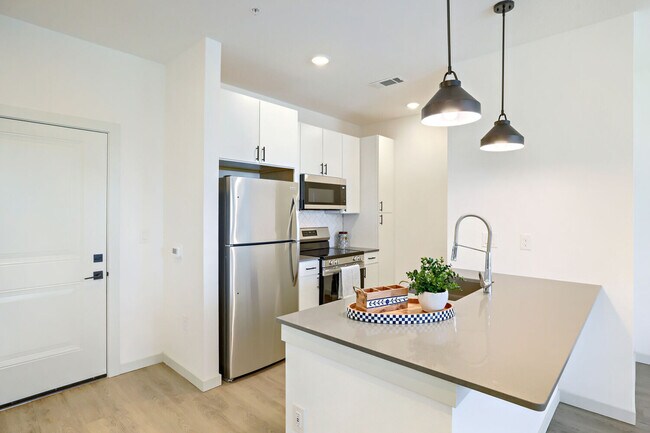 La cocina del modelo BH-A1 (L) incluye encimeras de cuarzo, un fregadero profundo de acero inoxidable y un juego completo de electrodomésticos. Garrett Harvest Junction West, Longmont, CO. - Garrett Harvest Junction West