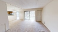 Located at 1015 Cloister Road in Wilmington, Delaware, this one-bedroom unit offers a thoughtfully organized single-floor layout. The open-plan living and dining area forms the heart of the home, finished with neutral wall-to-wall carpeting and bathed in natural light from large sliding glass doors fitted with vertical blinds. These doors provide a direct view of surrounding greenery, creating a calm, nature-facing backdrop. An elegant chandelier anchors the dining area, adding a refined touch to the open space.

The kitchen connects seamlessly to the living and dining area via a pass-through counter with dark stone-look countertops. Warm-toned wood cabinetry provides ample storage, complemented by a full-size refrigerator and tile flooring. A hallway leads to the utility panel and additional storage areas.

The spacious primary bedroom features plush carpeting, neutral walls, and a window with vertical blinds that invite natural light. A louvered double-door closet offers generous storage. An additional dedicated closet room further enhances storage capacity throughout the unit.

The overall ambiance is clean, bright, and understated, with a neutral color palette and practical finishes that create a comfortable and functional living environment.