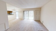 Located at 1015 Cloister Road in Wilmington, Delaware, this one-bedroom unit offers a thoughtfully organized single-floor layout. The open-plan living and dining area forms the heart of the home, finished with neutral wall-to-wall carpeting and bathed in natural light from large sliding glass doors fitted with vertical blinds. These doors provide a direct view of surrounding greenery, creating a calm, nature-facing backdrop. An elegant chandelier anchors the dining area, adding a refined touch to the open space.

The kitchen connects seamlessly to the living and dining area via a pass-through counter with dark stone-look countertops. Warm-toned wood cabinetry provides ample storage, complemented by a full-size refrigerator and tile flooring. A hallway leads to the utility panel and additional storage areas.

The spacious primary bedroom features plush carpeting, neutral walls, and a window with vertical blinds that invite natural light. A louvered double-door closet offers generous storage. An additional dedicated closet room further enhances storage capacity throughout the unit.

The overall ambiance is clean, bright, and understated, with a neutral color palette and practical finishes that create a comfortable and functional living environment.