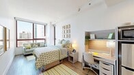 Located at 229 Duffield Street in the heart of Brooklyn, NY, this efficiently designed one-bedroom, one-bathroom unit makes excellent use of its compact footprint. The layout includes a hallway entry and two closets, providing practical storage solutions throughout.

The spacious bedroom serves as the central living area and is bathed in natural light through large floor-to-ceiling windows that frame striking urban views of the Brooklyn skyline. Warm hardwood flooring runs throughout, complementing the clean white walls and creating a bright, inviting atmosphere. The room accommodates a full-sized bed, nightstands, a seating area near the windows, and a built-in wood-toned desk and shelving unit — ideal for work or study. Framed botanical and art prints add personality to the walls.

The bathroom features a sleek, modern design highlighted by a full glass-enclosed walk-in shower with floor-to-ceiling tile work in contrasting dark and light tones, chrome fixtures, and a marble-topped vanity with a warm wood cabinet. Recessed lighting completes the clean, contemporary finish.

With a thoughtful layout, modern finishes, and abundant natural light, this unit offers a functional and stylish urban living experience in one of Brooklyn's most vibrant neighborhoods.
