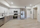 Located at 18412 Homestead Ave in Cutler Bay, FL, this well-appointed single-floor unit offers a thoughtfully designed layout across six rooms. The interior is finished with light wood-style flooring throughout, crisp white walls, and recessed lighting that lend a clean, modern aesthetic to the entire space.

The kitchen is a standout feature, showcasing a two-tone design with white upper cabinetry and warm taupe lower cabinets, a classic subway tile backsplash, and a full suite of stainless steel appliances including a range, microwave, dishwasher, and a side-by-side refrigerator with an in-door ice and water dispenser. The open layout connects the kitchen seamlessly to the main living area.

The bedrooms are bright and airy, each featuring large windows with roller shades that allow natural light to filter in while offering privacy, along with views of the surrounding greenery.

Two bathrooms serve the unit, both finished with neutral tile flooring and surrounds. One bathroom features a glass-enclosed walk-in shower, while the other includes a tub-shower combination — both equipped with modern vanities, white quartz countertops, large mirrors, and matte black hardware accents. The overall ambiance is contemporary, clean, and move-in ready.