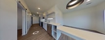 This contemporary 660 square foot apartment boasts a thoughtful single-floor design that maximizes space and functionality. The heart of the home is an open-concept kitchen and living area, seamlessly blending cooking and entertaining spaces. The kitchen features sleek white cabinetry, stainless steel appliances, and a subway tile backsplash, creating a clean and modern aesthetic.

Adjacent to the kitchen is a separate living room, offering flexibility in living arrangements. Both spaces are bathed in natural light, thanks to expansive windows that not only brighten the interior but also provide picturesque views of the surrounding area. The wood-look flooring throughout adds warmth and continuity to the space.

The apartment includes a well-appointed bathroom with a glass-enclosed shower, modern fixtures, and crisp white tilework. A sliding barn door in one of the rooms adds a touch of rustic charm to the otherwise contemporary design. Recessed lighting and strategically placed pendant fixtures ensure ample illumination throughout.

Storage solutions are integrated seamlessly, with built-in closets and kitchen storage optimizing the available space. The open layout and large windows create an airy, spacious feel that belies the apartment's modest square footage, making it an ideal living space for those seeking a modern, efficient home.