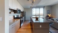 Located at 880 Pacific St in Solano, this thoughtfully designed two-bedroom, two-bathroom residence offers a seamless blend of modern aesthetics and functional living. The open-concept layout is anchored by expansive floor-to-ceiling windows and sliding glass doors that flood the space with natural light and frame sweeping views of the waterfront marina and surrounding cityscape.

The living area features warm hardwood flooring, a generous seating arrangement, and direct access to a private balcony overlooking the water — an ideal setting for both relaxing and entertaining. Adjacent to the living space, the dining area accommodates a glass-top table with contemporary seating.

The kitchen is well-appointed with stainless steel appliances, including a gas range, built-in microwave, and French door refrigerator. Light wood upper cabinetry contrasts with sleek gray lower cabinets, complemented by a tiled backsplash, track lighting, and a spacious center island with a quartz countertop.

Both bedrooms are comfortably sized with large windows offering city or waterfront views, hardwood flooring, and ample closet space. Each bathroom is finished with warm wood-look flooring, gray cabinetry, undermount sinks, and clean white tile surrounds in the shower enclosures, providing a polished, contemporary feel throughout.