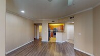 This single-floor residence offers a thoughtfully designed layout that balances functionality and comfort throughout. The open living area serves as the heart of the home, showcasing rich hardwood-style flooring, crown molding, and recessed lighting that create a polished, inviting atmosphere. Large windows fitted with blinds allow natural light to filter in, brightening the warm, neutral-toned walls found throughout the space.

The kitchen is well-equipped with warm wood cabinetry, granite countertops, a full suite of stainless steel appliances including a refrigerator, range, and microwave, and light tile flooring. A peninsula counter connects the kitchen to the main living area, making it ideal for both everyday use and entertaining.

The bedrooms are generously sized, each featuring the same hardwood-style flooring, ceiling fans with light fixtures, and windows that provide natural light and outdoor views. The rooms offer a calm, neutral palette well-suited for a variety of uses.

Both bathrooms are finished with tile flooring, wood vanity cabinetry, granite countertops, and tiled tub-shower combinations accented with warm tan tile banding. A dedicated in-unit laundry room houses a full-size washer and dryer, adding everyday convenience to this well-rounded residence.