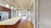 Located at 2525 Carlisle Street in Dallas, TX, this single-floor residence offers 920 square feet of thoughtfully designed living space across 3 bedrooms, 2 bathrooms, and 2 closets. The open-concept living area features rich hardwood flooring and floor-to-ceiling glass doors that lead to a private balcony with urban views, flooding the space with natural light. The kitchen is a standout feature, showcasing rich dark wood cabinetry, a mosaic tile backsplash, light stone countertops, stainless steel appliances including a range, microwave, and refrigerator, and a center island with pendant and track lighting overhead. The bedrooms are carpeted and equipped with ceiling fans; secondary bedrooms feature double windows with blinds providing ample natural light. The primary bedroom spans 160 square feet and is accompanied by a bathroom featuring a single vanity with dark wood cabinetry, stone countertops, large-format tile flooring, and a soaking tub with tile surround. Two walk-in closets with wire shelving systems offer generous storage throughout the unit.