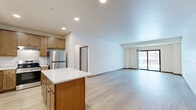 This well-appointed two-bedroom, three-bathroom residence in Shoreview, Minnesota offers a thoughtfully designed single-floor layout. The open-concept kitchen and living area serves as the heart of the home, featuring warm honey-toned cabinetry, a center island with a crisp white countertop, stainless steel appliances including a refrigerator and range, and recessed lighting throughout. Light wood-style flooring flows seamlessly through the main living space, which is filled with natural light and opens directly onto a private balcony through sliding glass doors, offering pleasant outdoor views. The spacious living area provides a clean, neutral canvas with warm wood baseboards adding a refined touch. Both bedrooms are carpeted and offer a comfortable, quiet retreat. The primary bedroom is generously sized and includes a walk-in closet with built-in shelving. Five closets total throughout the unit ensure ample storage. Each of the three bathrooms is finished with wood-toned vanities, white countertops, and tub-shower combinations. A dedicated laundry bathroom adds everyday convenience. The overall ambiance is clean, bright, and move-in ready, making this Shoreview residence a practical and comfortable home.