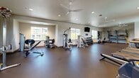 Located at 500 Roseville Pkwy in Roseville, California, this fitness center offers a generously sized, single-floor exercise space designed to accommodate a comprehensive workout experience. The room features durable dark rubber flooring throughout, providing a sturdy and safety-conscious surface suited for a wide variety of fitness activities.

The cardio section is well-appointed with a row of Matrix treadmills, elliptical trainers, and stationary and recumbent bikes, giving members ample options for aerobic exercise. Strength training is equally well-represented, with multiple cable and resistance machines, a full dumbbell rack, and various benches and functional training accessories organized along storage shelving.

Natural light fills the space through several large windows along the perimeter walls, creating a bright and energizing atmosphere. Ceiling fans are mounted overhead alongside recessed lighting, ensuring comfort and visibility throughout. Wall-mounted flat-screen televisions are positioned at multiple locations for entertainment during workouts.

A floor-to-ceiling mirror along one wall enhances the sense of openness and allows members to monitor their form. The entrance features glass double doors with access to an outdoor area, along with a water fountain conveniently located near the entry. The overall design is clean, functional, and welcoming, making this fitness center a practical and well-equipped facility for residents.