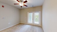 Located at 1005 Sonoran Cir in Summerville, SC, this single-floor home offers five bedrooms, two bathrooms, a kitchen, laundry room, and a central hallway connecting the layout. The kitchen is a standout feature, showcasing white shaker cabinetry, a white subway tile backsplash, stainless steel appliances, and a granite-topped peninsula with an undermount sink and pendant lighting — all set over light hardwood-style flooring. The open sight lines from the kitchen into the living areas enhance the sense of space throughout.

Each bedroom is carpeted and equipped with a ceiling fan, providing comfort and airflow. Several bedrooms feature French doors or large windows that bring in generous natural light and offer views of the surrounding greenery. The primary bedroom includes a walk-in closet with wire shelving for organized storage. Additional bedrooms also offer closet access and ample space.

The bathrooms are clean and functional, featuring white cabinetry, single-basin vanities with large mirrors, and tile flooring. A dedicated laundry room with wire shelving and utility hookups adds everyday convenience. The hallway, finished with light hardwood-style flooring, connects the rooms with a louvered closet door providing additional storage. Neutral wall tones throughout create a calm, cohesive aesthetic.