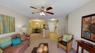 Located at 9407–9445 103rd St in Jacksonville, FL, this single-story residential unit offers a thoughtfully designed layout that balances comfort and functionality. The open-concept living area is a welcoming centerpiece, featuring plush carpeting, a ceiling fan with light fixture, and a sliding glass door that floods the space with natural light and provides direct access to an outdoor patio with views of surrounding greenery. The adjoining dining area is defined by a stylish pendant light overhead and offers an intimate setting ideal for everyday meals or entertaining.

The kitchen is efficiently arranged with light wood cabinetry, dark countertops, a full suite of white appliances including a refrigerator and range, and durable hardwood-style flooring that extends throughout the functional areas of the home.

The bedrooms are carpeted and generously proportioned, each offering closet storage. One bedroom features a bright window that brings in natural light, lending the room an airy feel.

The bathrooms are well-designed, with one featuring an elongated vanity with dark countertops, a large mirror, wood cabinetry, and a shower-tub combination. A second bathroom provides additional convenience with a toilet and shower area alongside closet access. The unit's neutral color palette and clean finishes create a cohesive, move-in-ready atmosphere throughout.