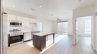 Located at 9990 E Harvard Ave in Denver, Colorado, this well-appointed 2-bedroom, 2-bathroom residence offers a thoughtfully designed single-floor layout with a clean, contemporary aesthetic throughout. Light-toned hardwood-style flooring flows seamlessly across all rooms, complementing the bright white walls and creating a cohesive, modern feel.

The open-concept kitchen and living area serves as the heart of the home. The kitchen is outfitted with a full suite of stainless steel appliances, including a refrigerator, range, microwave, and dishwasher. A two-tone cabinet design pairs rich dark wood lower cabinetry with crisp white upper cabinets, accented by a subway tile backsplash. A central island with a light countertop provides additional prep space and casual seating. The living area extends naturally from the kitchen and is bathed in natural light from a sliding glass door that opens to a private outdoor balcony, with a ceiling fan overhead adding comfort.

The spacious primary bedroom features its own sliding glass door with balcony access, a ceiling fan, and generous natural light. The second bedroom offers a large window with ample sunlight. Both bathrooms are finished with dark wood vanities, white countertops, and tub/shower combinations featuring subway tile surrounds and curved chrome curtain rods, maintaining the home's consistent modern style.