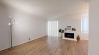 Located in the heart of Los Angeles at 467 N Arnaz Dr, this single-story residence offers a clean, well-maintained interior with a thoughtfully organized floor plan. The living room serves as the centerpiece of the space, featuring warm hardwood-style flooring, crown molding, and a classic white fireplace with a decorative mantle. A large sliding glass door fitted with vertical blinds floods the room with natural light while providing access to the outdoors. The open layout flows seamlessly into a dedicated dining area, distinguished by a pendant light fixture and continued hardwood-style flooring. The galley-style kitchen is efficiently designed, offering ample warm-toned wood cabinetry, granite-look countertops, a double basin sink, recessed lighting, and white appliances including a refrigerator and dishwasher. Light ceramic tile flooring completes the kitchen's clean, functional aesthetic. The bedrooms are comfortably sized, each featuring plush carpeting, neutral walls, and large windows with vertical blinds that invite generous amounts of natural light. The overall ambiance of the residence is bright and understated, with a consistent neutral palette throughout that provides a versatile canvas for any style of living.