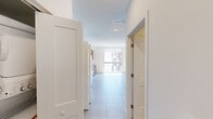 Located at 218 NW 8th St in Miami, FL, this single-floor unit offers a clean, contemporary design throughout. The layout flows from a wide entry hallway into an open living area bathed in natural light from a large floor-to-ceiling window that frames dynamic urban views of the surrounding Miami cityscape.

The kitchen is a standout feature, outfitted with warm wood-tone cabinetry extending to the ceiling and accented with sleek gold hardware. White subway tile backsplash contrasts beautifully against the cabinetry, while a full suite of stainless steel appliances — including a refrigerator, range, microwave, and dishwasher — provides a polished, functional workspace. A white quartz countertop with an undermount sink completes the look.

Light-toned large-format tiles run throughout the main living areas, contributing to a bright and airy atmosphere. The bathroom continues the cohesive design aesthetic with a wood-grain vanity, white countertop, and gold-accented lighting fixture above a wide mirror, all set against crisp white walls and tile flooring. Recessed lighting and a central HVAC system add modern comfort throughout the unit. A dedicated closet with built-in shelving provides practical storage. The overall design is minimal, modern, and move-in ready.