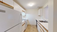Located at 195 Eastern Ave in Manchester, NH, this single-floor unit offers a well-organized layout designed for comfortable everyday living. The galley-style kitchen is efficiently arranged with white cabinetry featuring wood-trimmed accents, white appliances including a refrigerator, electric range, and dishwasher, a stainless steel sink, and durable tile flooring. A pass-through window connects the kitchen to the main living area, enhancing the open feel of the space. The living area is generously proportioned, finished with neutral carpet, and features a door leading to an outdoor balcony area, along with multiple windows that invite natural light. The bedrooms are carpeted and bright, each equipped with baseboard heating and windows overlooking the exterior. Two full bathrooms serve the unit, each featuring tile flooring, a vanity with countertop sink, and a tub-shower combination. Throughout the unit, a consistent neutral color palette of warm whites and beiges creates a clean, cohesive ambiance. Baseboard heating is present throughout, ensuring efficient climate control across all rooms.