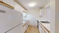 Located at 195 Eastern Ave in Manchester, NH, this single-floor unit offers a well-organized layout designed for comfortable everyday living. The galley-style kitchen is efficiently arranged with white cabinetry featuring wood-trimmed accents, white appliances including a refrigerator, electric range, and dishwasher, a stainless steel sink, and durable tile flooring. A pass-through window connects the kitchen to the main living area, enhancing the open feel of the space. The living area is generously proportioned, finished with neutral carpet, and features a door leading to an outdoor balcony area, along with multiple windows that invite natural light. The bedrooms are carpeted and bright, each equipped with baseboard heating and windows overlooking the exterior. Two full bathrooms serve the unit, each featuring tile flooring, a vanity with countertop sink, and a tub-shower combination. Throughout the unit, a consistent neutral color palette of warm whites and beiges creates a clean, cohesive ambiance. Baseboard heating is present throughout, ensuring efficient climate control across all rooms.