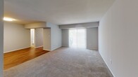 This single-floor residence offers a clean, functional layout designed for comfortable everyday living. The open living area is generously proportioned, featuring neutral-toned wall-to-wall carpeting and a large sliding glass door fitted with vertical blinds that allows abundant natural light to fill the space. A dedicated entryway with hardwood flooring provides a welcoming transition into the home.

The kitchen stands out as a highlight of the space, boasting modern white shaker-style cabinetry, light granite countertops, a classic white subway tile backsplash, and a full suite of stainless steel appliances including a range, over-the-range microwave, and dishwasher. Hardwood flooring extends throughout the kitchen, adding warmth and practicality.

The residence includes two well-sized bedrooms, each finished with plush carpeting and windows that bring in natural light. One bedroom features a closet and direct access to the hallway, offering a comfortable and private retreat.

The bathroom is neatly updated, featuring a full tub-shower combination, hardwood flooring, a white vanity with granite countertop, and a window for natural ventilation. Brushed nickel fixtures throughout the bathroom add a cohesive, contemporary touch. The overall palette of soft grays and whites creates a calm, neutral ambiance across the entire space.