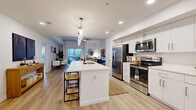 Located at 301 W Roosevelt St in the heart of Phoenix's vibrant Roosevelt Row neighborhood, this thoughtfully designed one-bedroom, three-bathroom residence offers a clean, contemporary aesthetic throughout. Light wood-tone flooring flows seamlessly across the open-concept living, dining, and kitchen area, creating a bright and cohesive feel. The modern kitchen is a standout, featuring crisp white cabinetry, quartz countertops, stainless steel appliances, and a large center island with bar seating illuminated by sleek pendant lighting — ideal for both everyday living and entertaining. The living area is spacious and well-lit, opening toward the dining space and sliding glass doors that lead to a generous private patio, perfect for outdoor relaxation. The primary bedroom is a comfortable retreat, offering room for a full suite of furnishings, a ceiling fan, natural light from a large window, and access to two closets. The elongated primary bathroom impresses with white vanity cabinetry, quartz surfaces, and a beautifully tiled marble walk-in shower. A stylishly appointed half bath features warm wood wall paneling and a clean vanity. Additional highlights include a pantry, in-unit laundry, and a well-organized layout that maximizes every square foot of this efficient yet refined Phoenix residence.