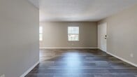 Located at 5011 Southside Dr in Louisville, KY, this single-floor, 2-bedroom, 1-bathroom home offers a practical and well-organized layout. The living room serves as the heart of the home, featuring durable wood-look plank flooring in a cool gray tone, neutral beige walls, and multiple windows that fill the space with natural light, creating a bright and welcoming atmosphere. A textured ceiling adds subtle character throughout.

The two bedrooms are carpeted for comfort, each dressed in the same warm neutral tones. The primary bedroom is generously sized, offering ample room for furnishings, and features a large louvered bi-fold closet, a window for natural light, and direct hallway access. The second bedroom also features plush carpeting and a window, making it a versatile space suitable as a guest room or home office.

The bathroom is neatly appointed with wood-look vinyl flooring, a full-size soaking tub with an integrated shower surround, a toilet, and a white vanity with cabinet storage below, providing functional everyday convenience.

A connecting hallway ties all rooms together efficiently, while the overall neutral color palette and clean finishes throughout make this home a move-in ready, comfortable residence.