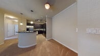 Located at 6601 S West Shore Blvd in Tampa, Florida, this single-floor residence offers a thoughtfully designed layout that blends functionality with modern style. The open-concept living and dining area features warm neutral carpeting, crown molding, and a ceiling fan with light fixture, creating a comfortable and inviting atmosphere. A sliding glass door with blinds allows natural light to fill the living space while providing access to the outdoors.

The kitchen is a standout feature, showcasing rich dark espresso cabinetry, dark granite countertops, and a stylish mosaic tile backsplash. Stainless steel appliances — including a French door refrigerator with ice maker, microwave, and range — complement the modern aesthetic. A curved breakfast bar peninsula separates the kitchen from the living area, with pendant lighting and track lighting adding both task and ambient illumination. Tile flooring runs throughout the kitchen.

The bedrooms are carpeted and generously proportioned, with ample natural light from window treatments. At least one bedroom includes access to a walk-in closet. The bathroom features large-format earth-toned wall tiles surrounding a soaking tub and shower combination, paired with light tile flooring and clean, contemporary fixtures. Overall, the space presents a cohesive and functional design well-suited to Tampa living.