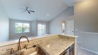 Located at 1327 Finger Lakes in Dayton, Ohio, this single-story, 3-bedroom, 2-bathroom home offers a well-designed layout with a comfortable and neutral aesthetic throughout. The kitchen is a standout feature, equipped with rich dark cabinetry, light granite-style countertops, stainless steel appliances including a refrigerator, range, and microwave, and durable wood-style flooring that extends into the adjoining areas. The open living room impresses with soaring vaulted ceilings, a ceiling fan, plush wall-to-wall carpeting, and access to an outdoor deck, along with windows that invite abundant natural light and views of surrounding greenery. The spacious primary bedroom features soft carpeting, a natural light-filled window, and direct access to a private bathroom with dark cabinetry. The two additional bedrooms are well-proportioned, each with plush carpet, natural light from windows with views of the outdoors, and ample closet space. One bedroom features vaulted ceilings and wood-style flooring, adding variety to the home. Both bathrooms include tub/shower combinations with clean, white surrounds and chrome fixtures. A connecting hallway ties all rooms together, completing this functional and inviting single-story home.