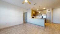 This single-floor residence offers a thoughtfully designed layout that balances functionality with a clean, contemporary aesthetic throughout. Light-toned luxury vinyl plank flooring runs continuously across the living areas and bedrooms, creating a cohesive and easy-to-maintain foundation for the entire space.

The open-concept kitchen serves as a central focal point, featuring taupe-toned cabinetry, a classic subway tile backsplash, and a full suite of stainless steel appliances including a refrigerator with ice and water dispenser, a gas range, and a built-in microwave. A peninsula with a light countertop and pendant lighting overhead provides additional prep space and casual seating, opening seamlessly into the living area, which is equipped with a ceiling fan.

Multiple bedrooms offer bright, airy environments, each featuring ceiling fans, natural light through blinded windows, and closet access. The rooms maintain a neutral color palette that lends itself well to a variety of furnishing styles.

The unit includes two bathrooms: one with a glass-enclosed walk-in shower featuring marble-style tile surrounds and overhead cabinetry, and a second with a full soaking tub and shower combination, similarly finished with coordinating tile and taupe cabinetry. Both bathrooms continue the light wood-look flooring found throughout the home, reinforcing the space's consistent and modern design language.