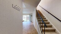 This two-story, two-bedroom, two-bathroom home in Boulder, Colorado offers a practical and comfortable layout spread across two well-proportioned floors. The main level welcomes you through an entrance with a coat rack wall, opening into a bright, open-concept living, dining, and kitchen area. Wood-look flooring flows throughout the main level, complementing the neutral tones of the space. The living room is anchored by a striking stone-surround fireplace and features a sliding glass door that fills the room with natural light and provides direct access to a private patio. The kitchen is thoughtfully equipped with warm wood cabinetry, a stainless steel refrigerator, electric range, dishwasher, and an extended tile-topped breakfast bar that connects the kitchen to the living and dining areas. A carpeted staircase with a metal railing leads to the upper floor, where both bedrooms are located. Each bedroom features plush carpet, track lighting, window blinds, and baseboard heating. The spacious primary bedroom also includes a wall-mounted air conditioning unit and ample natural light from multiple windows. Three closets provide generous storage throughout. Two full bathrooms, each with a tub-shower combination, complete the layout. Textured ceilings add a classic finishing touch throughout the home.