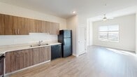 Located at 1250 NW 36th St in Miami, FL, this well-appointed one-bedroom, one-bathroom unit offers a thoughtfully designed layout across a single floor. Light wood-style flooring runs throughout, creating a cohesive and contemporary aesthetic.

The open-concept kitchen and living area form the heart of the unit. The kitchen features warm wood-tone cabinetry in an L-shaped configuration, light countertops, a double-basin sink, and a full suite of black appliances including a refrigerator, range, microwave, and dishwasher. The adjoining living area is bright and airy, benefiting from recessed lighting, a ceiling fan, and a large window that frames scenic treetop and cityscape views.

The bedroom is a comfortable and sun-filled retreat, highlighted by an elevated tray ceiling, a ceiling fan, and a wide window offering expansive outdoor views. Its direct access to both the bathroom and an additional room adds to the functional flow of the space.

The bathroom is well-equipped with a dual-sink vanity topped with light stone counters, wood-tone cabinetry, a large mirror with overhead lighting, and a full bathtub with tiled surround. A dedicated laundry room houses a full-size side-by-side washer and dryer with overhead shelving, adding everyday convenience to this Miami residence.