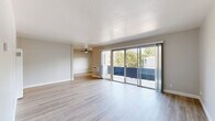 Located at 1250 Walker Ave in Walnut Creek, California, this two-bedroom, one-bathroom residence offers a well-designed single-floor layout with a clean, modern aesthetic throughout. Light-toned hardwood-style flooring runs continuously through the main living areas, lending a cohesive and bright feel to the space.

The open living room is a standout feature, anchored by large sliding glass doors that lead to a private balcony overlooking mature trees. A ceiling fan adds functionality, while the textured ceiling and neutral wall tones create a comfortable, welcoming ambiance. An adjacent dining or secondary living area flows naturally from the main room.

The galley-style kitchen is thoughtfully updated, featuring white shaker cabinetry, granite-look countertops, stainless steel appliances including a refrigerator and range, and warm wood-tone flooring. Ample upper and lower cabinet storage maximizes the efficient layout.

Both bedrooms are carpeted in wood-style flooring with neutral walls and generous natural light. The primary bedroom includes a double mirrored-door closet with built-in shelving, offering practical storage. The second bedroom is equally well-proportioned and versatile.

The bathroom is neatly finished with a white vanity, granite countertop, undermount sink, and a full tub-shower combination, complemented by wood-style flooring that ties the space together cohesively.
