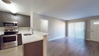 Located at 2450 Hilton Head Place in El Cajon, CA, this single-floor residence offers a thoughtfully designed open-concept layout that seamlessly connects the kitchen and living areas. The living room features durable wood-style flooring, neutral gray walls, and a front entry door with a transom window that invites natural light. Vertical blinds cover a sliding glass door, providing access to an outdoor area while offering flexible light control.

The kitchen is a standout feature, outfitted with dark wood cabinetry extending floor to ceiling for generous storage, a suite of stainless steel appliances including a refrigerator, electric range, and over-the-range microwave, and a light-toned countertop with an undermount sink. A breakfast bar peninsula connects the kitchen to the main living area, enhancing the open flow of the space.

A dedicated laundry area is accessible just off the kitchen. The bedroom is carpeted for comfort and benefits from multiple windows fitted with vertical blinds, allowing ample natural light. The bathroom is clean and modern, featuring a white undermount vanity sink, a large mirror with built-in side shelving, and a neutral color palette throughout. The overall ambiance of the home is clean, bright, and move-in ready.