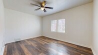 Located at 416 SW Fourth St in Topeka, Kansas, this single-floor, one-bedroom unit offers a thoughtfully utilized layout that maximizes every inch of its compact footprint. The main living area is anchored by rich, wood-look plank flooring that runs throughout, lending warmth and visual continuity to the space. A ceiling fan with integrated lighting is centrally positioned overhead, providing both airflow and ambient light. Neutral white walls keep the interior feeling bright and clean, while two windows with horizontal blinds allow natural light to filter in and offer views of the surrounding greenery outside.

The kitchenette is seamlessly tucked into a corner of the main room and features gray cabinetry, a white gas range, and a sink — providing essential cooking functionality without occupying excessive space. A full bathroom is accessible directly from the main living area and includes a toilet, bathtub with shower, and a vanity with additional cabinet storage. Floor vents provide climate control throughout the unit. The entry door is solid and positioned near the kitchen, contributing to a practical flow within the space. Overall, this unit presents a clean, functional living environment well-suited for single occupancy in downtown Topeka.