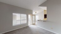 Located at Rampart Court in Fort Mitchell, Kentucky, this single-floor residence offers a thoughtfully designed layout with a range of functional and aesthetic features throughout. The living area is a standout space, anchored by soaring vaulted ceilings that lend an open, airy feel, complemented by soft carpeting and a tile-surround fireplace with a classic hearth — an inviting focal point for the room. Large windows fitted with blinds allow natural light to fill the space, while a glass-panel French door provides direct access to a private outdoor deck, seamlessly blending interior and exterior living. An open pass-through breakfast bar connects the living area to the kitchen, which is well-appointed with dark cabinetry, light countertops, black appliances including a refrigerator, range, and dishwasher, and wood-look tile flooring. The bedrooms are generously proportioned, each featuring plush carpeting and large windows that invite ample daylight. The bathrooms are cleanly finished with dark vanity cabinetry, mirrored medicine cabinets, and wood-look tile floors. A walk-in closet is accessible from one of the bathrooms, adding practical storage. Throughout, the neutral color palette and clean finishes create a bright, move-in-ready environment.