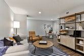 This single-floor residence located along Jasmine Pkwy in Roswell, GA offers a thoughtfully arranged layout with distinct living zones unified by a neutral gray palette and wood-look flooring throughout the main areas. The open-concept living and dining space provides generous room for both relaxing and entertaining, with recessed lighting overhead and a seamless transition between zones. A geometric metal world map accent on the dining wall adds a contemporary artistic touch, complementing the clean, modern aesthetic carried throughout.

The galley-style kitchen is well-appointed with two-tone cabinetry — white upper cabinets paired with charcoal lower cabinets — white countertops, stainless steel appliances including a refrigerator, range, and dishwasher, and a deep single-basin sink. Natural light filters in through a window at the far end, brightening the corridor layout.

The bedroom features plush carpeting, corner windows with drape panels, and a ceiling fan with light fixture, creating a comfortable, restful environment. An adjacent bathroom showcases a wide vanity with dark cabinetry, white countertop, a large framed mirror, and a tall storage tower.

A versatile flex room, accessed through a multi-pane French door, offers wood-look flooring and a window — suitable for use as a home office or secondary sleeping space.