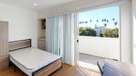Located at 1539 Beloit Ave in the sought-after West Los Angeles neighborhood of 90025, this modern single-floor residence showcases clean contemporary design throughout. The open, light-filled hallway with warm hardwood flooring and crisp white walls creates a welcoming flow between rooms.

The kitchen is thoughtfully designed with sleek grey cabinetry, stone-look countertops with subtle flecked detailing, a textured tile backsplash, and stainless steel appliances including a gas range and built-in microwave. A double-basin sink and ample counter space make this a highly functional cooking area.

Multiple bedrooms offer comfortable living with plush carpeting, mirrored sliding closet doors providing generous storage, and modern wood-and-metal bed frames. One bedroom features direct access to a private balcony through sliding glass doors, offering views of surrounding palm trees and abundant natural light.

The bathrooms are finished to a high standard, featuring large-format white wall tiles, frameless glass shower enclosures, light wood-toned cabinetry, and polished chrome fixtures. One bathroom includes a soaking tub with a glass sliding door, while another offers a spacious walk-in shower with both overhead and handheld fixtures. A third bathroom provides a compact, well-organized layout with overhead storage. The overall ambiance is clean, modern, and move-in ready.