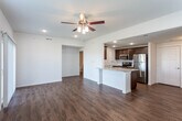 Located at 5400 Overland Dr in Lawrence, Kansas, this single-floor residence offers a well-designed, open-concept layout that seamlessly connects the main living areas. Rich hardwood-style flooring flows throughout the living and dining spaces, complemented by clean white walls and ceiling fans with integrated lighting that enhance both comfort and brightness.

The kitchen is a functional centerpiece of the home, featuring dark espresso cabinetry, granite countertops, a breakfast bar peninsula, and a full suite of stainless steel appliances including a refrigerator, electric range, and microwave. Recessed lighting illuminates the space efficiently. The kitchen opens directly to the expansive living area, which benefits from natural light streaming through multiple windows and a sliding glass door leading to the outdoors.

The bedroom is generously sized, finished with plush carpeting, a ceiling fan, and a wide bank of windows offering views of the surrounding neighborhood. The bathroom is appointed with a granite-topped dark wood vanity, hardwood-style flooring, and a full soaking tub and shower combination. A dedicated laundry area houses a full-sized side-by-side washer and dryer with overhead wire shelving for added storage. The overall design is clean, modern, and move-in ready.