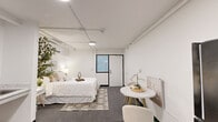 Located at 1612 Sisk Rd in Modesto, California, this single-floor studio unit offers a clean, modern aesthetic defined by bright white walls, track lighting, and a seamless open layout. The main living area combines sleeping and dining functions within a compact yet efficiently organized footprint. A full-size bed anchors the sleeping zone, set atop a patterned area rug over grey carpeting, while a small round marble-top dining table with two upholstered chairs provides a dedicated sitting and dining space nearby. A mini-fridge is conveniently positioned along the wall, adding practical functionality to the living area. A kitchenette with a stainless steel sink and light-toned countertop is integrated into the space, complemented by light wood-look vinyl flooring that transitions seamlessly from the adjoining bathroom. A wall-mounted mini-split HVAC unit ensures individual climate control. The bathroom is thoughtfully designed with accessibility in mind, featuring a roll-under vanity with a wall-mounted mirror, grab bars, a built-in shower seat, and a combination tub and shower enclosed by a curtain rod. Crisp white walls and light flooring throughout contribute to a bright, airy ambiance, making this studio a functional and comfortable space.