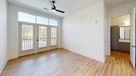 This 670 square foot apartment in Huntersville, NC, showcases a thoughtful design that maximizes space and functionality. The single-floor layout comprises one bedroom, one bathroom, a kitchen, and a closet. The primary bedroom, measuring 130 square feet, offers ample space and is illuminated by large windows with white blinds, providing natural light and outdoor views.

The kitchen is a standout feature, boasting a modern design with a mix of white upper cabinets and gray lower cabinets. Stainless steel appliances, including a refrigerator, microwave, and range, complement the sleek aesthetic. A central island with a light-colored countertop serves as both a prep area and potential dining space.

Throughout the apartment, warm wood-look flooring creates a cohesive and inviting atmosphere. The bathroom showcases a contemporary vanity with ample storage and a crisp white countertop. A well-organized closet with wire shelving offers practical storage solutions.

High ceilings and recessed lighting contribute to the sense of spaciousness, while a ceiling fan in the living area ensures comfort. French doors leading to a balcony provide additional outdoor living space and natural light. The overall design emphasizes clean lines, neutral colors, and modern fixtures, creating a stylish and efficient living environment.