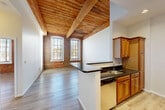 Located at 4 Bishop St in Framingham, MA, this one-bedroom, one-bathroom unit showcases the character of a thoughtfully converted historic building. The open-concept living area immediately impresses with its signature exposed red brick walls and original wood-planked ceilings supported by substantial timber beams, lending an authentic industrial-loft aesthetic throughout. Light wood flooring runs seamlessly across the main living space, complementing the warm tones of the brick and wood overhead.

Tall arched windows flood the living room with generous natural light, framing views of the surrounding area while highlighting the textural richness of the brick walls. The kitchen is positioned at the heart of the unit, anchored by a peninsula with dark granite countertops, warm wood cabinetry, and a full suite of stainless steel appliances including a gas range, microwave, and refrigerator. In-unit laundry adds everyday convenience.

The spacious bedroom features the same light wood flooring, soaring ceilings with exposed beams, an original arched brick window, and access to two closets. The bathroom is clean and functional, complete with a full tub and shower. A dedicated entrance and hallway complete this well-appointed unit, offering a distinctive blend of historic charm and modern comfort.