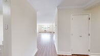 This single-floor residence offers a functional and well-organized layout encompassing three bedrooms, two bathrooms, a living room, kitchen, dedicated closet, and two hallways. The interior is finished with warm hardwood-style flooring that runs consistently throughout, complementing the clean, neutral wall tones that lend a bright, airy feel to every room.

The spacious living room is bathed in natural light from large windows that offer leafy outdoor views, with baseboard heating ensuring year-round comfort. The kitchen features a pass-through window opening to the living area, white cabinetry with modern hardware, light stone-look countertops, a stainless steel sink, and stainless steel appliances including a refrigerator, microwave, and range.

The primary bedroom is a generously sized retreat, highlighted by a large window with natural views and a mirrored sliding closet. The two additional bedrooms are well-proportioned, each with mirrored sliding closets and ceiling fans, offering practical storage and comfortable living space.

The primary bathroom is tiled in classic white subway tile with a decorative mosaic border accent, and is equipped with a soaking tub, shower, pedestal sink, and a mirrored medicine cabinet. The second bathroom features chrome fixtures and clean, simple finishes. Two hallways connect the rooms efficiently, creating a smooth flow throughout the residence.