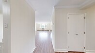 This single-floor residence offers a functional and well-organized layout encompassing three bedrooms, two bathrooms, a living room, kitchen, dedicated closet, and two hallways. The interior is finished with warm hardwood-style flooring that runs consistently throughout, complementing the clean, neutral wall tones that lend a bright, airy feel to every room.

The spacious living room is bathed in natural light from large windows that offer leafy outdoor views, with baseboard heating ensuring year-round comfort. The kitchen features a pass-through window opening to the living area, white cabinetry with modern hardware, light stone-look countertops, a stainless steel sink, and stainless steel appliances including a refrigerator, microwave, and range.

The primary bedroom is a generously sized retreat, highlighted by a large window with natural views and a mirrored sliding closet. The two additional bedrooms are well-proportioned, each with mirrored sliding closets and ceiling fans, offering practical storage and comfortable living space.

The primary bathroom is tiled in classic white subway tile with a decorative mosaic border accent, and is equipped with a soaking tub, shower, pedestal sink, and a mirrored medicine cabinet. The second bathroom features chrome fixtures and clean, simple finishes. Two hallways connect the rooms efficiently, creating a smooth flow throughout the residence.