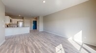Located at 186 Main St in Auburn, Maine, this thoughtfully designed one-bedroom, one-bathroom unit offers a clean, modern aesthetic throughout its well-utilized single floor. The open-concept kitchen and living area serves as the heart of the unit, where light wood-tone flooring, neutral walls, and abundant natural light create a bright and welcoming atmosphere. The kitchen is well-appointed with crisp white shaker cabinetry, marble-look quartz countertops, a peninsula with additional storage, and a full suite of stainless steel appliances including a refrigerator, electric range, microwave, and dishwasher. The adjacent living area benefits from a sliding glass door and a flanking window that frame striking views of the waterway and Auburn cityscape beyond, with direct access to a private balcony. The bedroom features plush carpeting, dual windows overlooking the water, and a stylish sliding barn door that connects to the en-suite bathroom. The bathroom is finished with wood-look flooring, a marble-top vanity with an undermount sink, a walk-in shower, and a dedicated toilet area. A hallway with a bold blue entry door completes the unit's functional and contemporary layout.