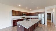 Located at 121 Marigny St. in Moncks Corner, SC, this two-story home offers a thoughtfully designed layout spread across two floors. The main level opens into a bright, open-concept kitchen and living area finished with light hardwood-style flooring and recessed lighting. The kitchen is a standout feature, showcasing rich dark cabinetry, granite countertops, a large center island with a built-in sink, and stainless steel appliances including a refrigerator, range, and microwave. A ceiling fan and a decorative chandelier add character to the living space, while a rear door with an adjacent window fills the area with natural light. The attached garage offers a clean concrete floor and overhead door. Upstairs, four bedrooms provide comfortable accommodations, including a generously sized primary bedroom. The bedrooms feature plush carpeting and closets with wire shelving systems, including a walk-in closet. Three well-finished bathrooms are distributed throughout the home, each featuring granite-topped vanities with dark wood cabinetry and tub-shower combinations. A dedicated laundry room houses a full-size washer and dryer with overhead wire shelving, adding everyday convenience to this functional and modern home.