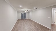 Located at Fairfield Townhouses at Holbrook in Holbrook, NY, this thoughtfully renovated single-floor townhouse showcases a clean, modern aesthetic with consistent finishes carried throughout. Light gray walls, crisp white crown molding, and wide-plank wood-look flooring create a cohesive and contemporary feel across all living areas. Recessed lighting and ceiling fans are present in the main living spaces, which also feature sliding glass doors dressed with vertical blinds, allowing natural light to filter in. The galley-style kitchen is a standout feature, offering white shaker cabinetry, quartz countertops, a marble-style tile backsplash, and a full suite of stainless steel appliances including a gas range, built-in microwave, refrigerator, and dishwasher. A gold-toned faucet adds a refined accent at the sink. The bedroom areas continue the same flooring and trim details, with one room featuring a built-in closet with shelving and hanging storage. The bathroom is outfitted with white subway tile, a soaking tub, and a frameless sliding glass shower enclosure with brushed nickel hardware. The overall ambiance is fresh, clean, and move-in ready.