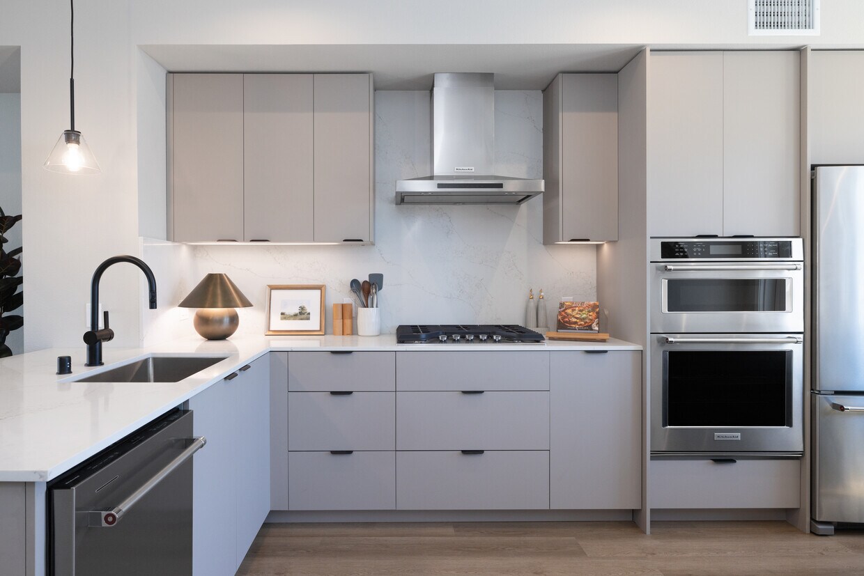 Cocina de casa adosada de 3 habitaciones Signature Collection I con gabinetes de color gris claro, encimeras de cuarzo de mármol blanco y electrodomésticos de acero inoxidable renovados. - Avalon Pleasanton