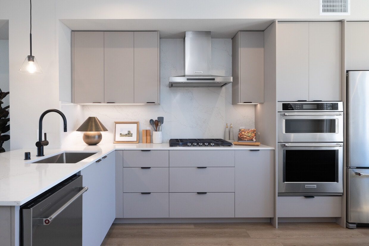 Signature Collection I 3-Bedroom Townhome Kitchen with light grey cabinetry, white marbled quartz countertops, and upgraded stainless steel appliances - Avalon Pleasanton