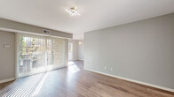 This single-floor unit offers a clean, modern aesthetic highlighted by wood-look flooring that flows consistently throughout the entire space. The living area is bright and open, benefiting from abundant natural light streaming in through large sliding glass doors fitted with vertical blinds that lead to an outdoor view of surrounding greenery. A contemporary multi-arm light fixture adds a stylish focal point to the living space, which also features a closet near the entry for added convenience.

The kitchen is thoughtfully designed with white cabinetry accented by brushed nickel hardware, light quartz-style countertops, a stainless steel single-basin sink, and a stainless steel gas range. A gray subway tile backsplash adds a modern touch, complementing the overall neutral color palette.

The bedrooms are well-sized, featuring soft neutral wall tones, wood-look flooring, and windows that invite natural light. Generously sized bi-fold closets with wire shelving provide practical storage solutions.

The bathroom is stylishly appointed with gray stone-look tile flooring, a tub-shower combination featuring a dramatic stacked stone tile surround, and a white vanity with storage. The cohesive gray tones create a spa-like ambiance. Overall, the unit presents a refreshed, move-in-ready interior with a consistent modern design language throughout.