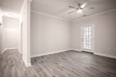 Located at 6767 Iron Bridge Rd in North Chesterfield, Virginia, this single-floor residence offers a thoughtfully designed layout with contemporary finishes throughout. Light wood-tone luxury vinyl plank flooring runs through the main living areas, complementing the neutral warm-gray walls and bright white trim that create a cohesive, modern aesthetic.

The open-concept living and dining area features crown molding, a ceiling fan with integrated lighting, and a decorative column accent that subtly defines the space. Natural light filters in through the windows, and the layout flows seamlessly into the kitchen. The kitchen is well-equipped with rich dark-brown cabinetry, light granite-style countertops, a stainless steel refrigerator, black range and microwave, a dishwasher, and a pendant-lit breakfast bar with sink.

The bedrooms are carpeted for comfort, each outfitted with ceiling fans and generous closet space, including walk-in closets with multi-tier shelving. One bedroom offers an exterior-facing window with neighborhood views. The bathrooms include a soaking tub with white subway tile surround, wood-toned vanity cabinetry, and light vinyl flooring that ties back to the main living areas, maintaining a consistent design throughout.